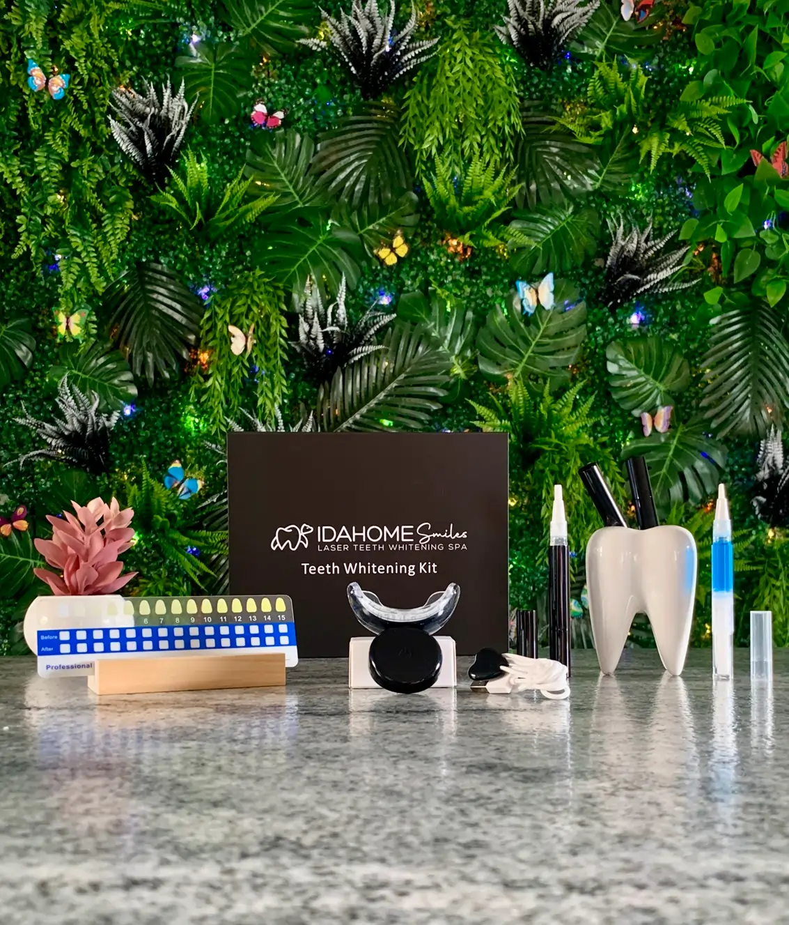Comprehensive display of Idahome Smiles' Polar Perfection Teeth Whitening Kit against a lush green botanical backdrop with vibrant neon accents. The set includes a professional shade guide, three Polar Pen Teeth Whitening Touch-Up Pens, a custom mouth tray, LED light, and a Glacial Guard Remineralizing & Desensitizing Gel, emphasizing the brand's commitment to enamel health and sustainability.